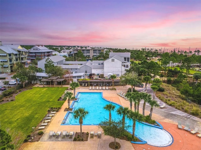 pool at dusk with a patio and a yard