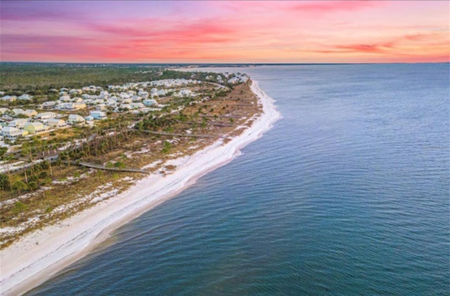 aerial view at dusk with a water view and a beach view