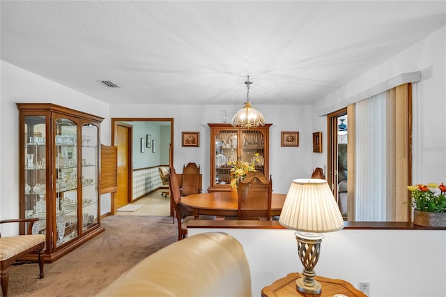 carpeted dining room featuring an inviting chandelier