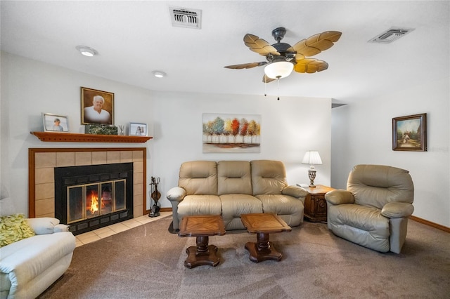 living room with ceiling fan, a tile fireplace, and light carpet