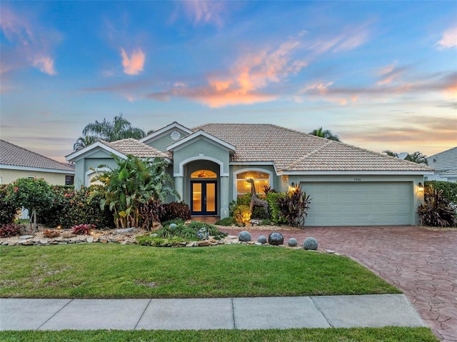 view of front of home with french doors, a lawn, and a garage