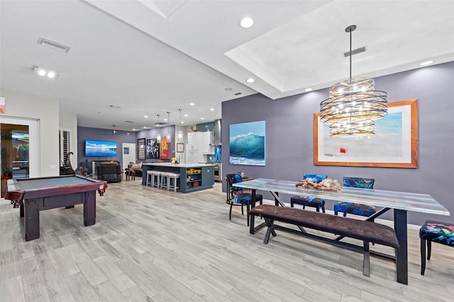 playroom featuring pool table, light hardwood / wood-style flooring, a tray ceiling, and bar