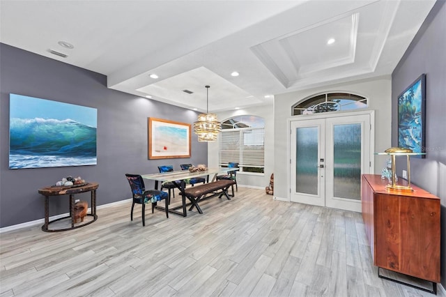 dining room with an inviting chandelier, light hardwood / wood-style flooring, a tray ceiling, and french doors