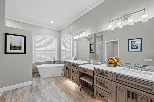 bathroom with wood-type flooring, ornamental molding, vanity, and a bathtub