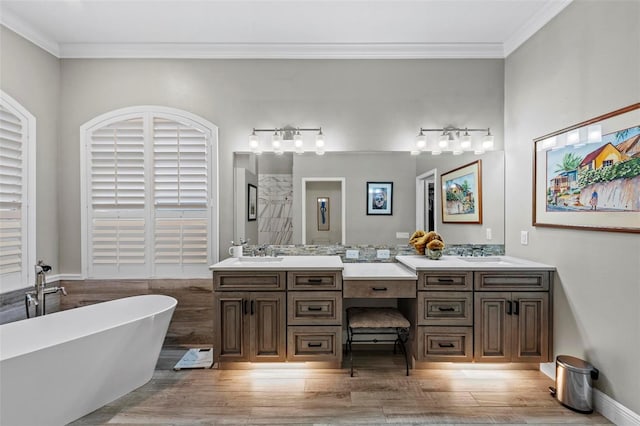 bathroom with hardwood / wood-style flooring, a tub to relax in, vanity, and crown molding