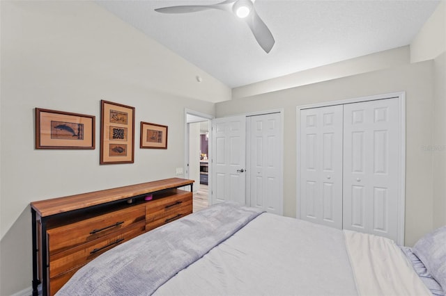 bedroom with ceiling fan, two closets, and lofted ceiling