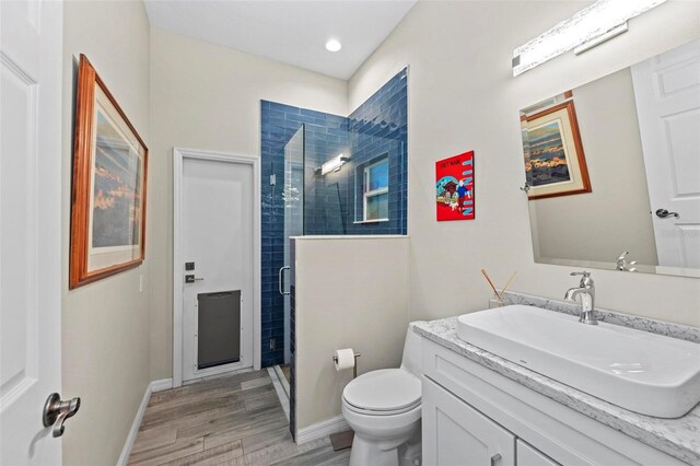 bathroom featuring a shower with door, hardwood / wood-style floors, toilet, and vanity