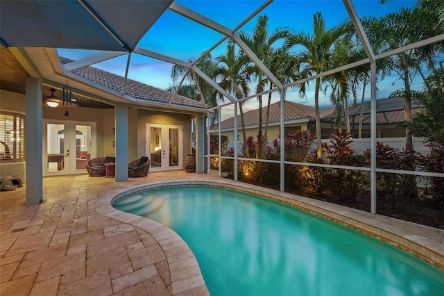 pool at dusk with a lanai, a patio area, and french doors