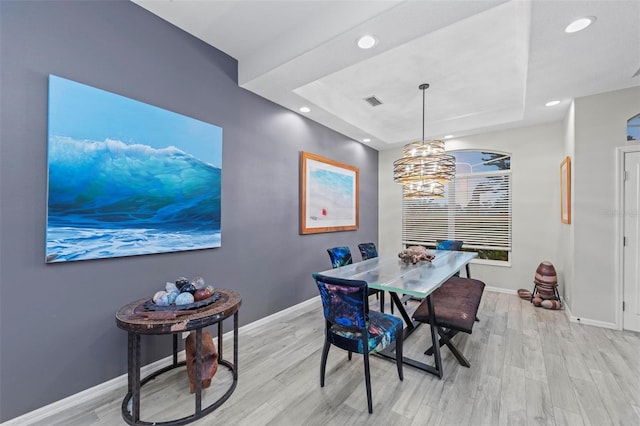 dining room featuring light hardwood / wood-style floors and a tray ceiling