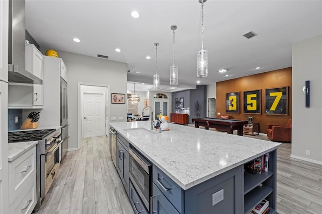 kitchen featuring sink, stainless steel appliances, white cabinetry, and an island with sink