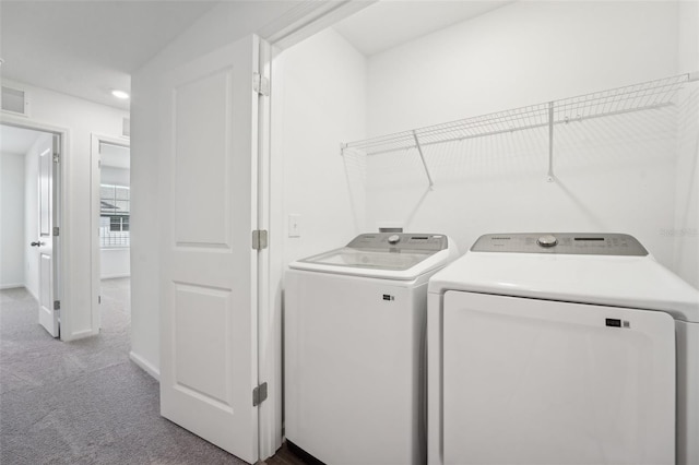 clothes washing area with light colored carpet and washer and dryer