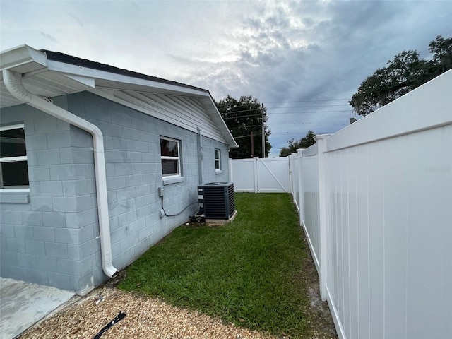 view of side of property with central AC unit and a lawn