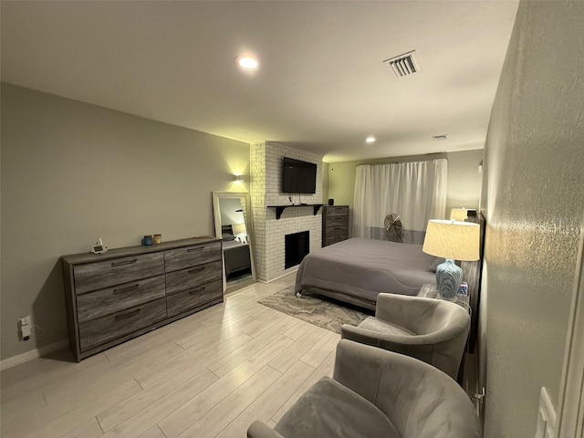 bedroom featuring a brick fireplace and light hardwood / wood-style flooring