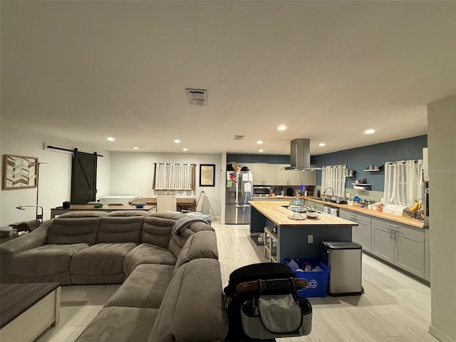 living room featuring a barn door, sink, and light wood-type flooring