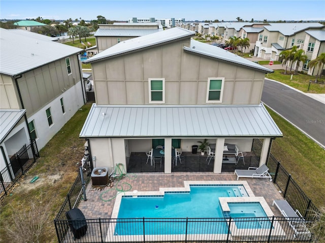 back of property featuring cooling unit, a patio area, and a swimming pool with hot tub