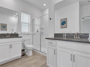 bathroom featuring vanity, toilet, a shower with door, and hardwood / wood-style flooring