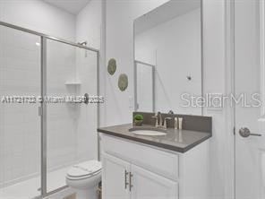 bathroom featuring toilet, walk in shower, and vanity