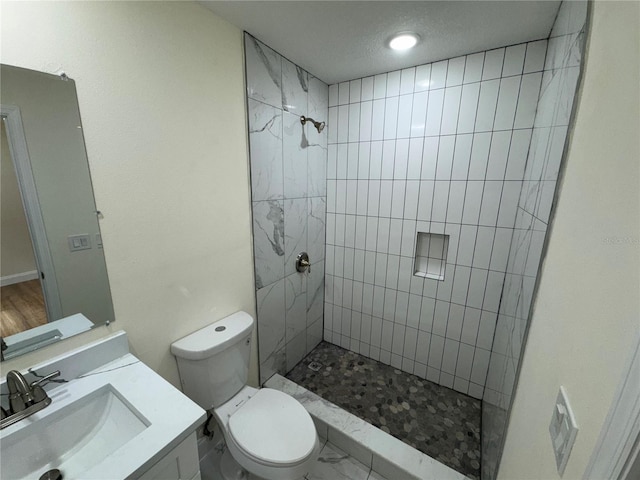 bathroom featuring vanity, toilet, and tiled shower