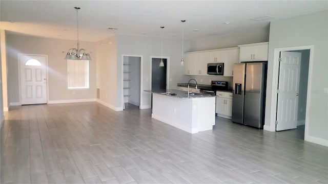 kitchen with a notable chandelier, white cabinetry, decorative light fixtures, stainless steel appliances, and a center island with sink