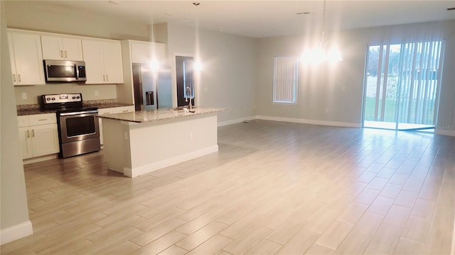 kitchen with sink, white cabinets, stainless steel appliances, and a kitchen island with sink