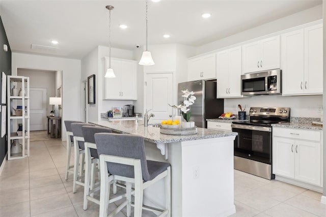 kitchen with light stone counters, white cabinetry, appliances with stainless steel finishes, and hanging light fixtures