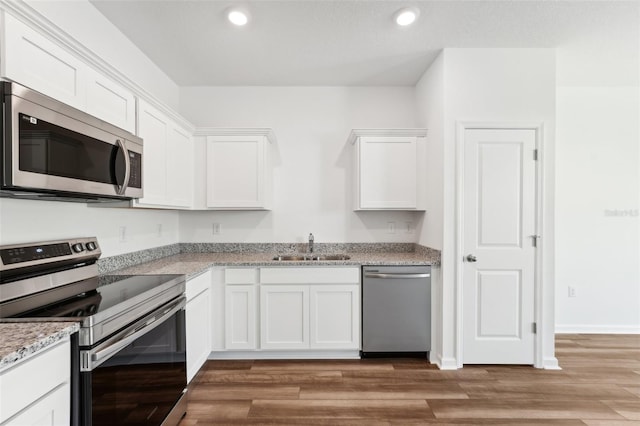 kitchen featuring appliances with stainless steel finishes, light stone counters, sink, light wood-type flooring, and white cabinetry