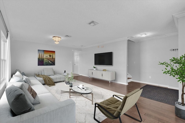 living area featuring visible vents, crown molding, baseboards, wood finished floors, and a textured ceiling