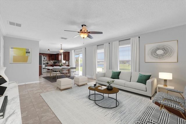 living room with light tile patterned floors, visible vents, ornamental molding, and a ceiling fan