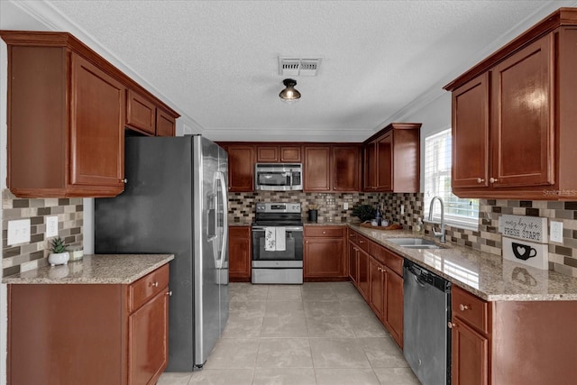 kitchen featuring a sink, light stone counters, visible vents, and stainless steel appliances