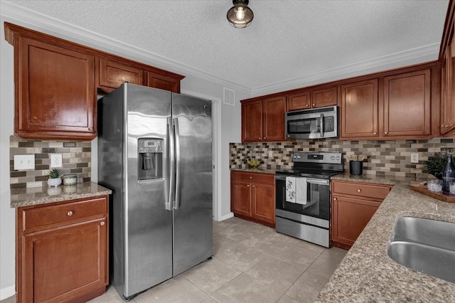 kitchen with a sink, tasteful backsplash, a textured ceiling, stainless steel appliances, and light tile patterned floors