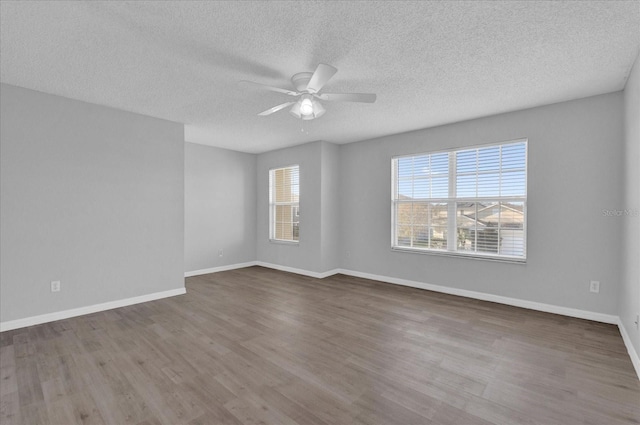 spare room featuring a ceiling fan, wood finished floors, baseboards, and a textured ceiling