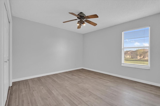 unfurnished room with ceiling fan, baseboards, a textured ceiling, and wood finished floors