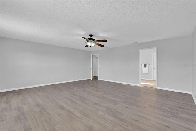 unfurnished room featuring a textured ceiling, wood finished floors, baseboards, and ceiling fan