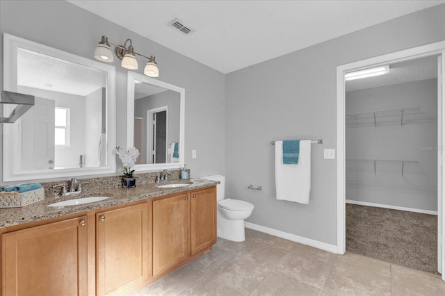 full bath with a spacious closet, visible vents, toilet, and a sink