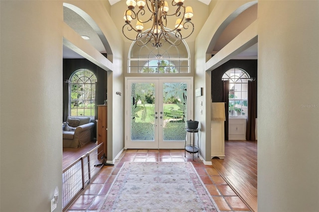 entryway featuring a towering ceiling, a chandelier, french doors, and tile patterned flooring