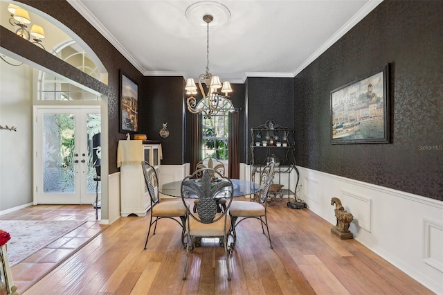 dining room with crown molding, hardwood / wood-style flooring, a chandelier, and french doors