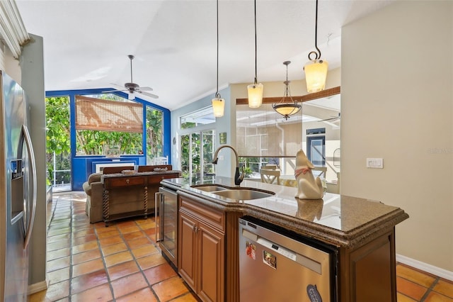 kitchen featuring a kitchen island with sink, sink, pendant lighting, stainless steel appliances, and lofted ceiling