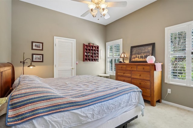 bedroom with light carpet, multiple windows, a closet, and ceiling fan