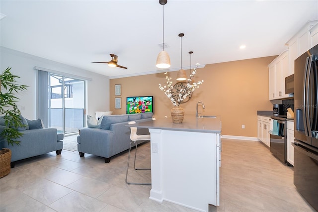 kitchen featuring decorative light fixtures, white cabinetry, a kitchen island with sink, a breakfast bar, and stainless steel electric range