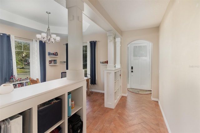 hall featuring an inviting chandelier, light parquet flooring, and ornate columns