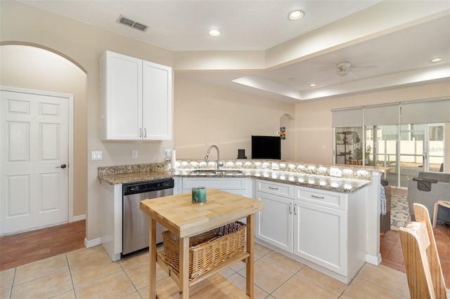 kitchen with sink, light tile patterned floors, dishwasher, light stone counters, and white cabinets