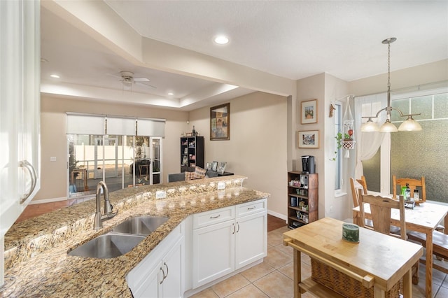 kitchen with sink, hanging light fixtures, light stone countertops, white cabinets, and light tile patterned flooring