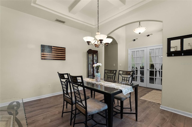 dining room featuring arched walkways, dark wood-type flooring, coffered ceiling, visible vents, and baseboards