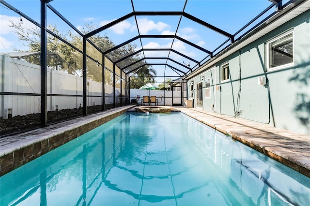 view of pool with a lanai, a fenced backyard, a pool with connected hot tub, and a patio