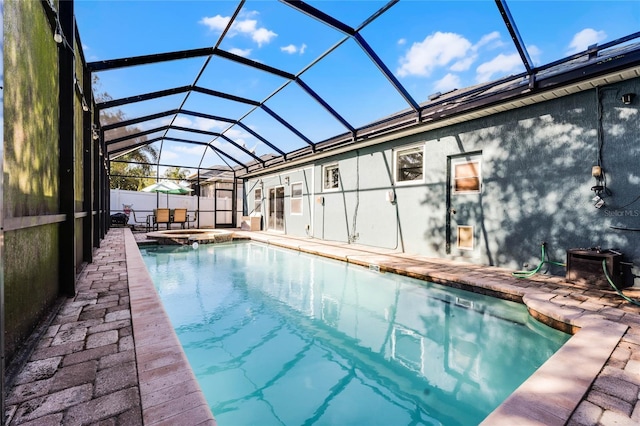 view of pool featuring a pool with connected hot tub, a lanai, a patio, and fence