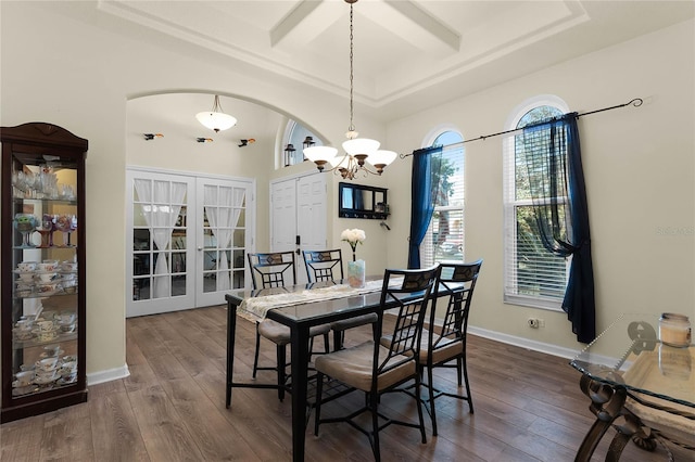 dining room featuring arched walkways, french doors, wood finished floors, coffered ceiling, and baseboards