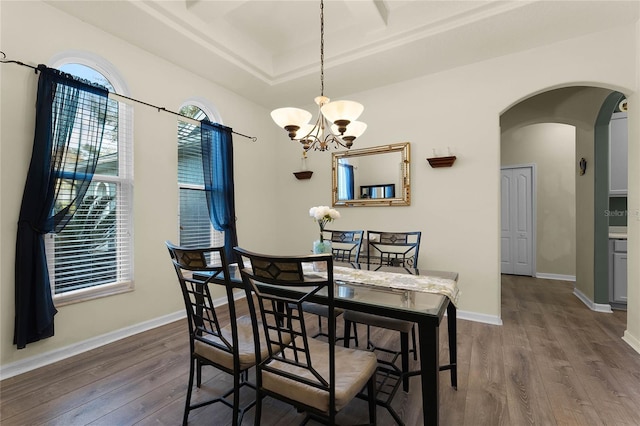 dining space featuring a chandelier, arched walkways, baseboards, and wood finished floors