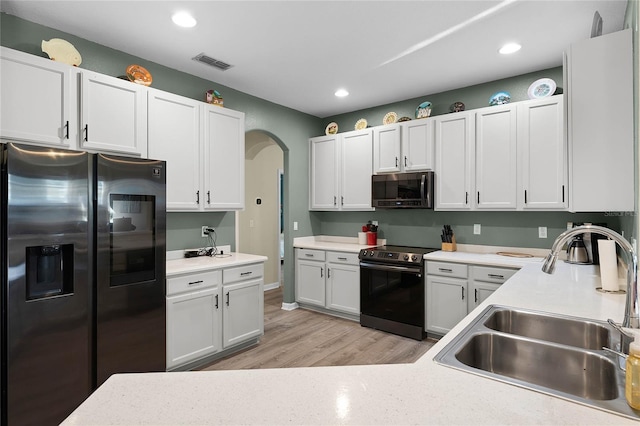 kitchen featuring stainless steel appliances, light countertops, visible vents, white cabinets, and a sink