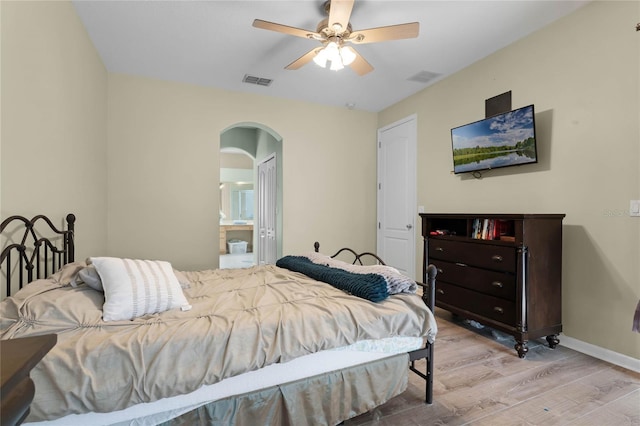 bedroom featuring light wood-type flooring, arched walkways, visible vents, and baseboards