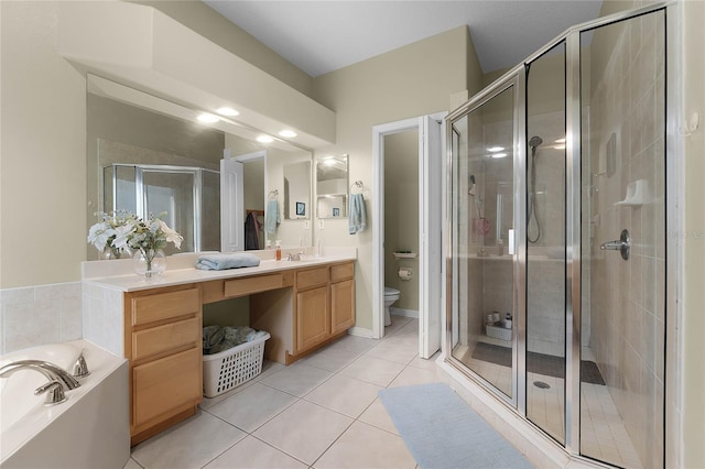 bathroom featuring double vanity, a stall shower, toilet, and tile patterned floors